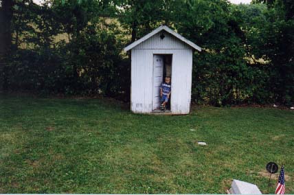 Snapshot of a child at an old outhouse, not a gravestone