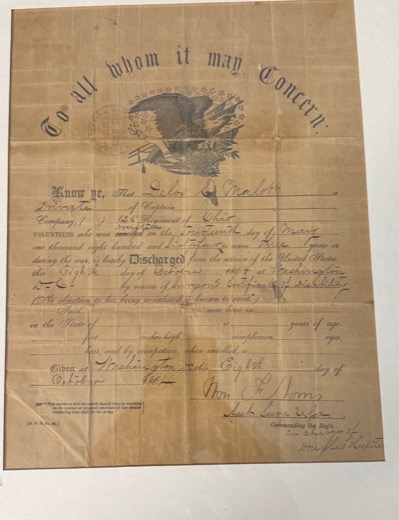 The original 1864 discharge of Delos C. Malott, printed with an eagle and the words To all whom it may concern, on aged, folded paper in a frame