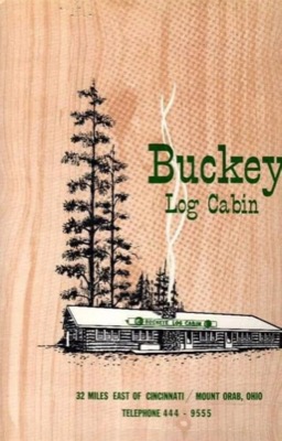 Wood-grain matchbook cover with a drawing of the Buckeye Log Cabin under tall pines, reading Buckeye Log Cabin, 32 miles east of Cincinnati, Mount Orab, Ohio